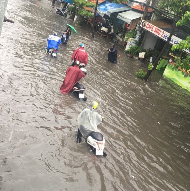 Mưa lớn kéo dài hơn 30 phút, người Sài Gòn bì bõm lội nước, té ngã vì nhiều tuyến đường ngập nặng - Ảnh 1.