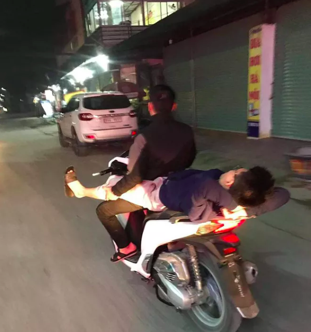 Nam thanh niên nằm duỗi chân, gác vào đùi người lái xe máy đang phóng với tốc độ cao khiến nhiều người sợ hãi - Ảnh 1.