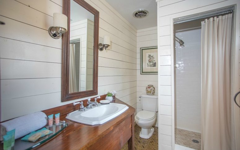 08-the-bathroom-is-done-with-white-shiplap-and-tiles-a-walk-in-shower-and-a-vanity-of-rich-stained-wood-775x484-1585497174970234667477.jpg
