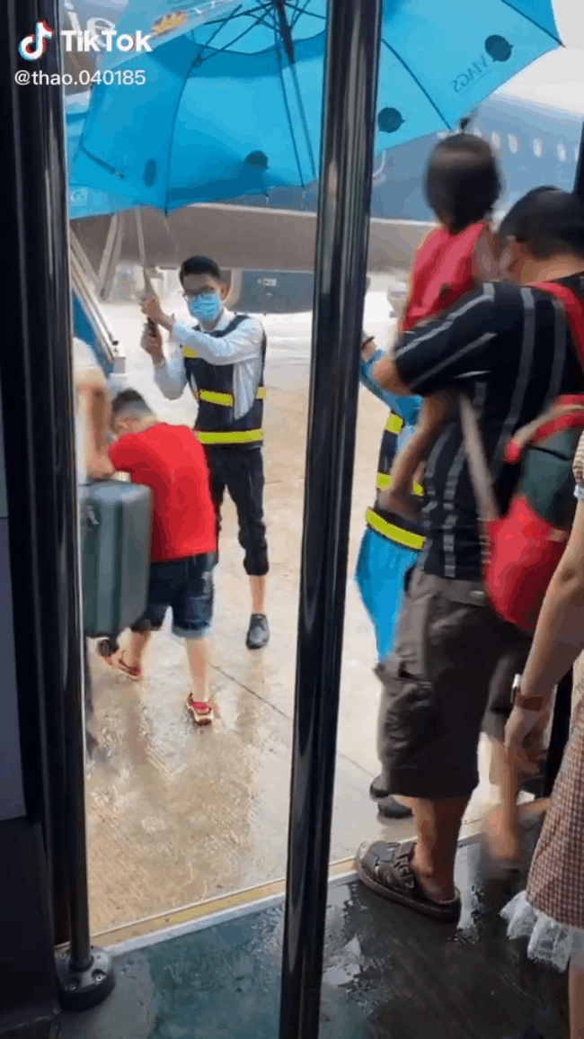 Cộng đồng mạng xúc động với hình ảnh 2 nhân viên Vietnam Airlines ướt đầm mình, đứng cầm ô che cho khách lên máy bay giữa trời mưa to - Ảnh 2.