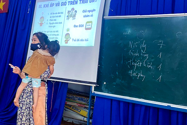 Touching image of a teacher holding a child in her arms while passionately teaching in class - Photo 1.