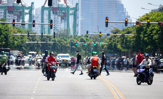 Đường Hà Nội hoá "ảo ảnh" dưới cái nắng gần 40 độ, nhiều người tranh thủ núp dưới bóng cây lúc chờ đèn đỏ mà không biết có thể "rơi" mất tiền! - Ảnh 1.