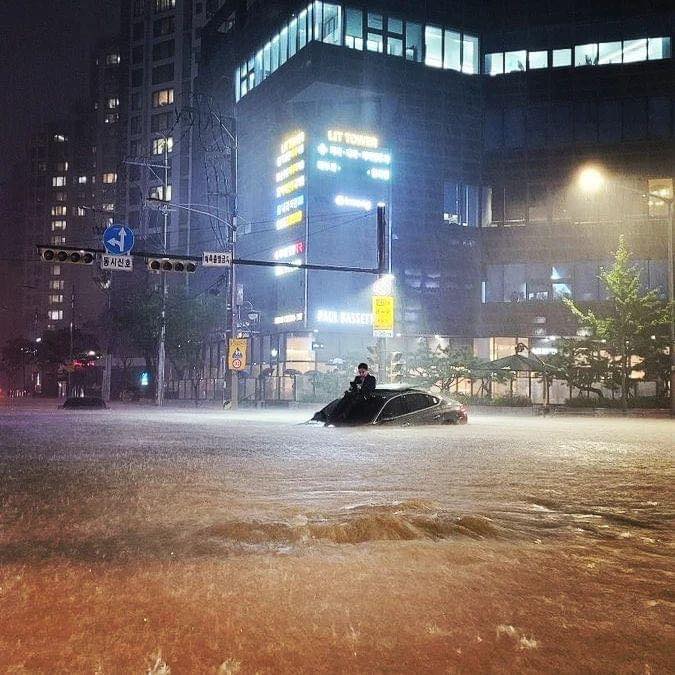 Ảnh gây bão mạng trong trận mưa lịch sử ở Seoul: Người đàn ông bị kẹt trên nóc xe sang - Ảnh 1.