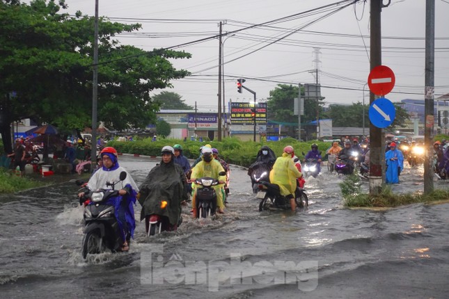 Mưa trắng trời, người dân TPHCM xách dép lội bì bõm trên quốc lộ - Ảnh 1.