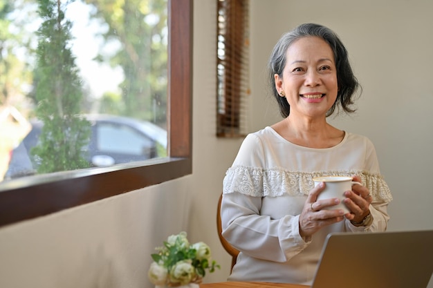 happy-60s-retired-asian-woman-holding-tea-cup-smiling-looking-camera67155-29562-16977974216381588700903-1708438820887552694500-1708507743270-1708507743496181737325.jpg