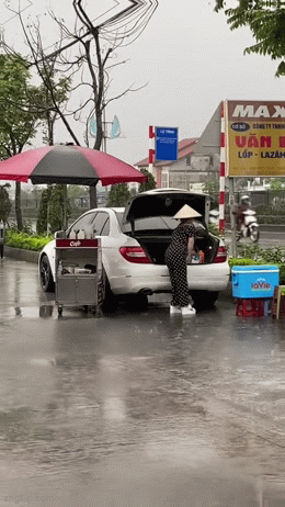 Hành động lạ bên cạnh chiếc ô tô của người phụ nữ bán nước dưới cơn mưa nặng hạt khiến dân mạng đứng hình - Ảnh 1. Hành động lạ bên cạnh chiếc ô tô của người phụ nữ bán nước dưới cơn mưa nặng hạt khiến dân mạng đứng hình - Ảnh 1.