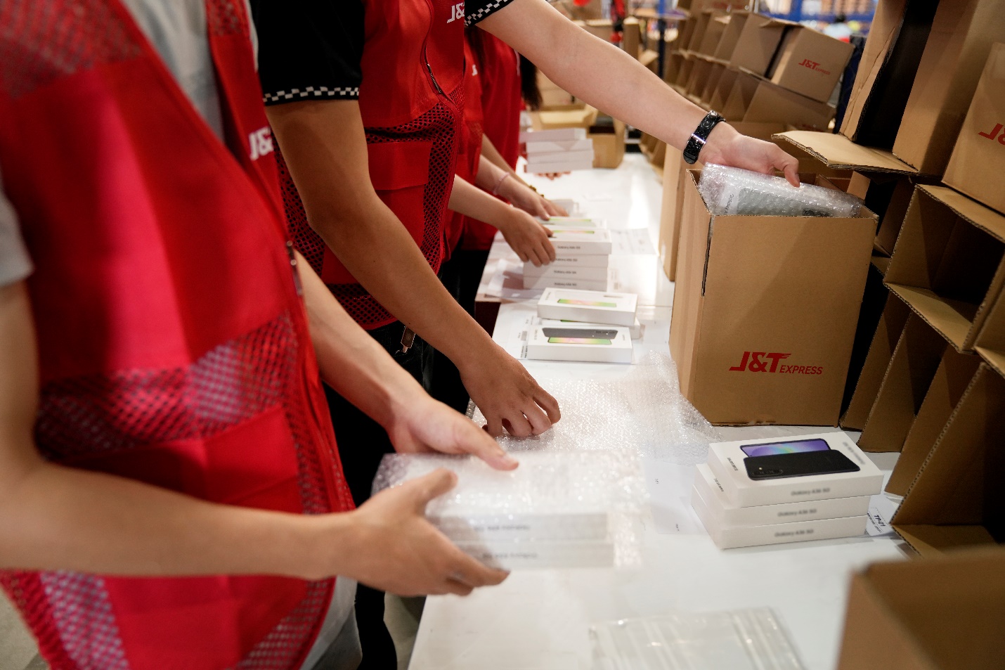 J&T Express trở thành đối tác vận chuyển các sản phẩm công nghệ cho Samsung Việt Nam- Ảnh 1. A group of workers packing boxes AI-generated content may be incorrect.
