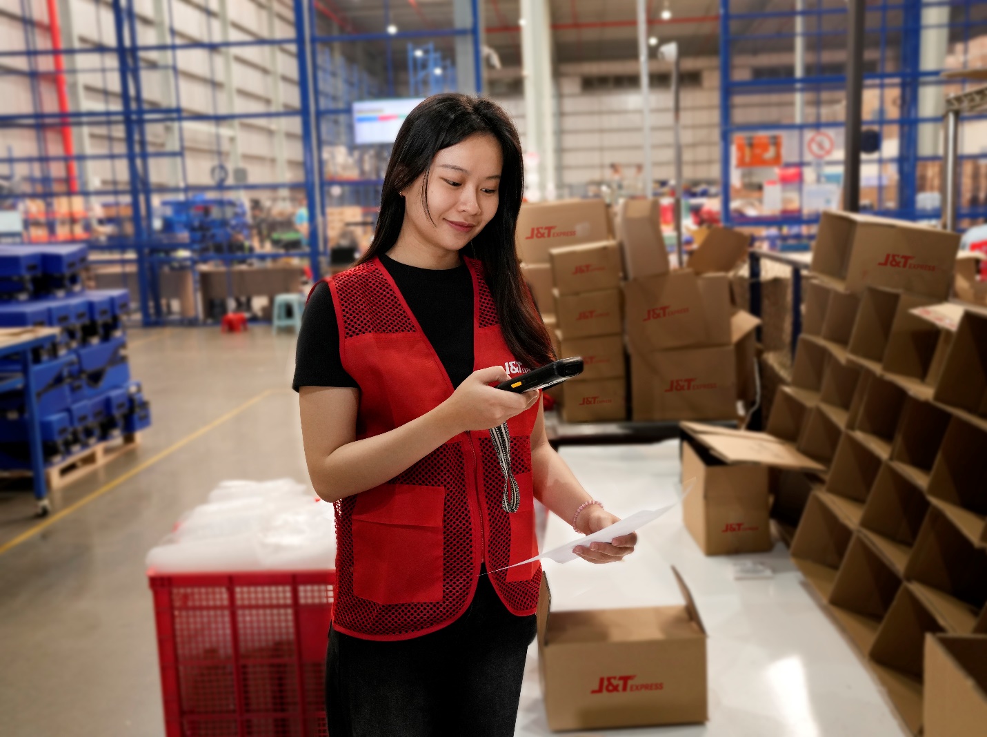J&T Express trở thành đối tác vận chuyển các sản phẩm công nghệ cho Samsung Việt Nam- Ảnh 2. A person in a warehouse holding a phone AI-generated content may be incorrect.