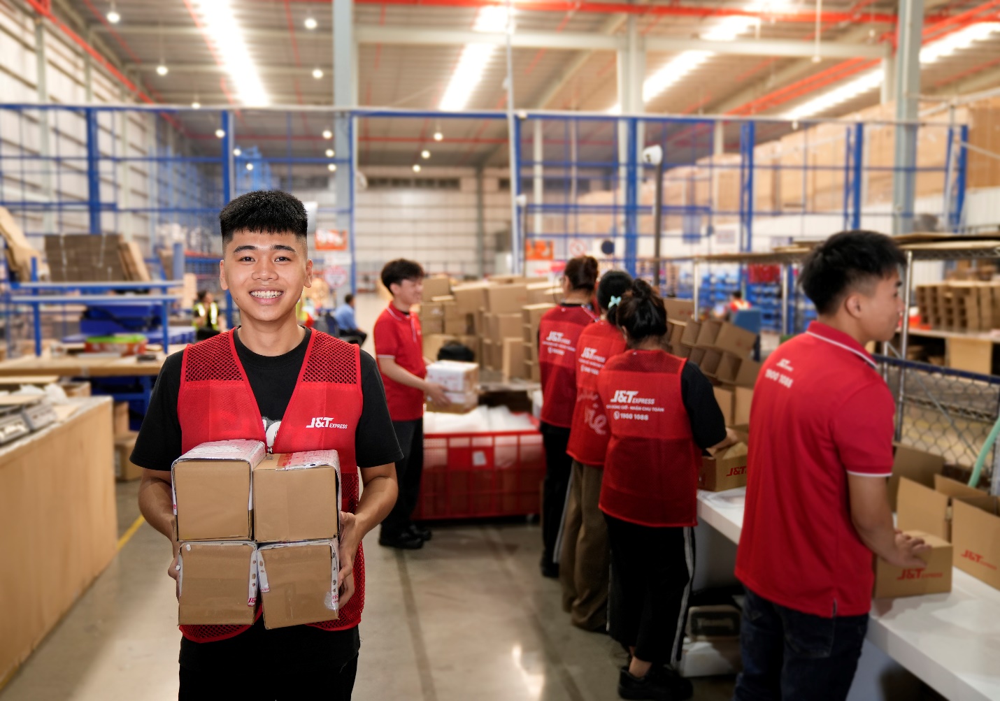 J&T Express trở thành đối tác vận chuyển các sản phẩm công nghệ cho Samsung Việt Nam- Ảnh 3. A person holding a stack of boxes AI-generated content may be incorrect.