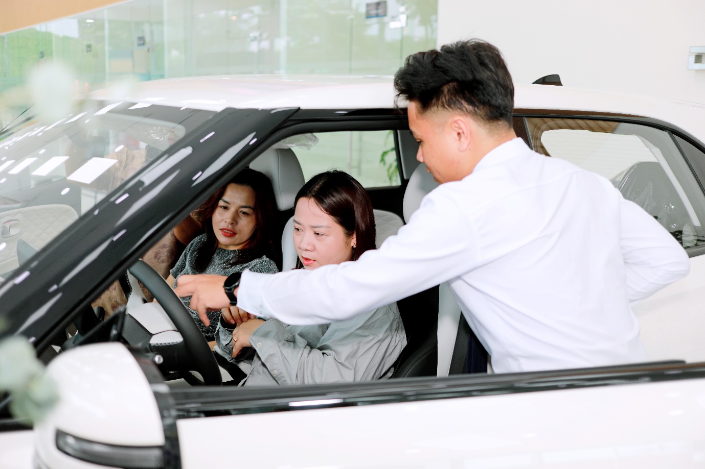 Hismart trao tặng xe điện Dongfeng Box cho đại lý: Kết nối thương hiệu, gắn bó cộng đồng - Ảnh 2. A person showing a person something in the car AI-generated content may be incorrect.