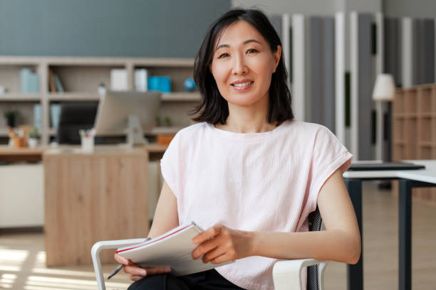 attractive-asian-businesswoman-smiling-while-holding-notebook-in-office-17547551829282088447882-1754798215473-17547982156541618914203.jpg