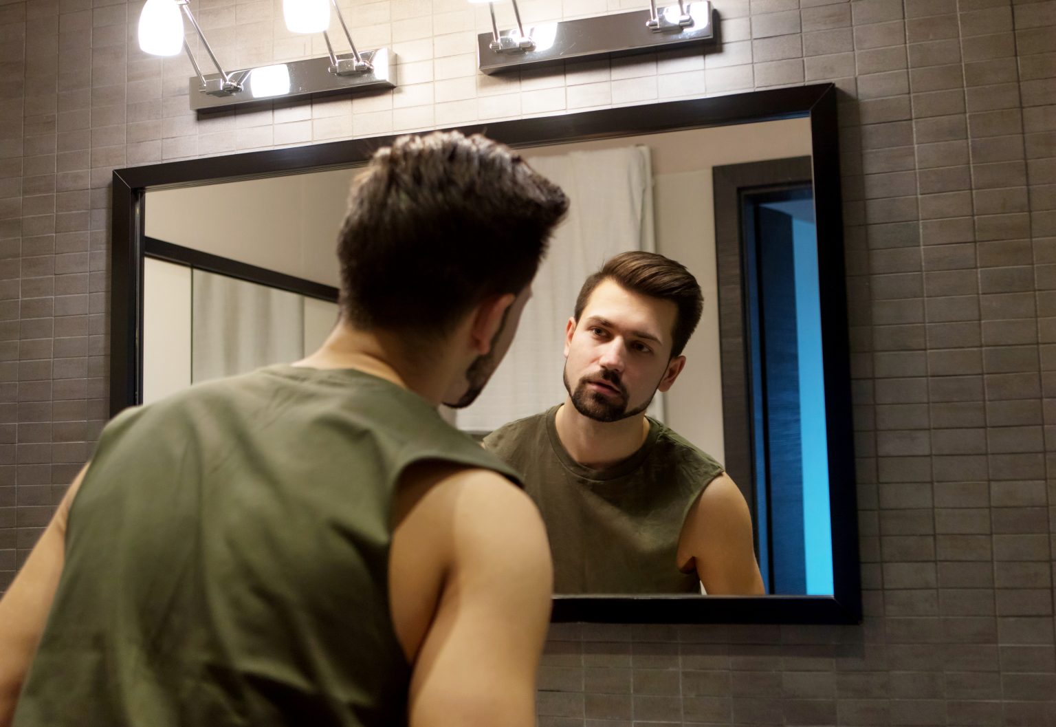 rear-view-young-man-looking-mirror-while-standing-home-1536x1057-17558296957691473385877-1755830584385-17558305848252042543376-1755907757955-1755907758027865639171.jpg