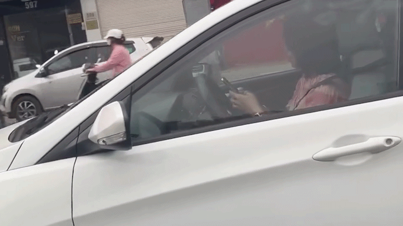 Nữ t&agrave;i xế d&ugrave;ng 2 tay bấm điện thoại trong l&uacute;c đang l&aacute;i xe tr&ecirc;n phố H&agrave; Nội - Ảnh 1.