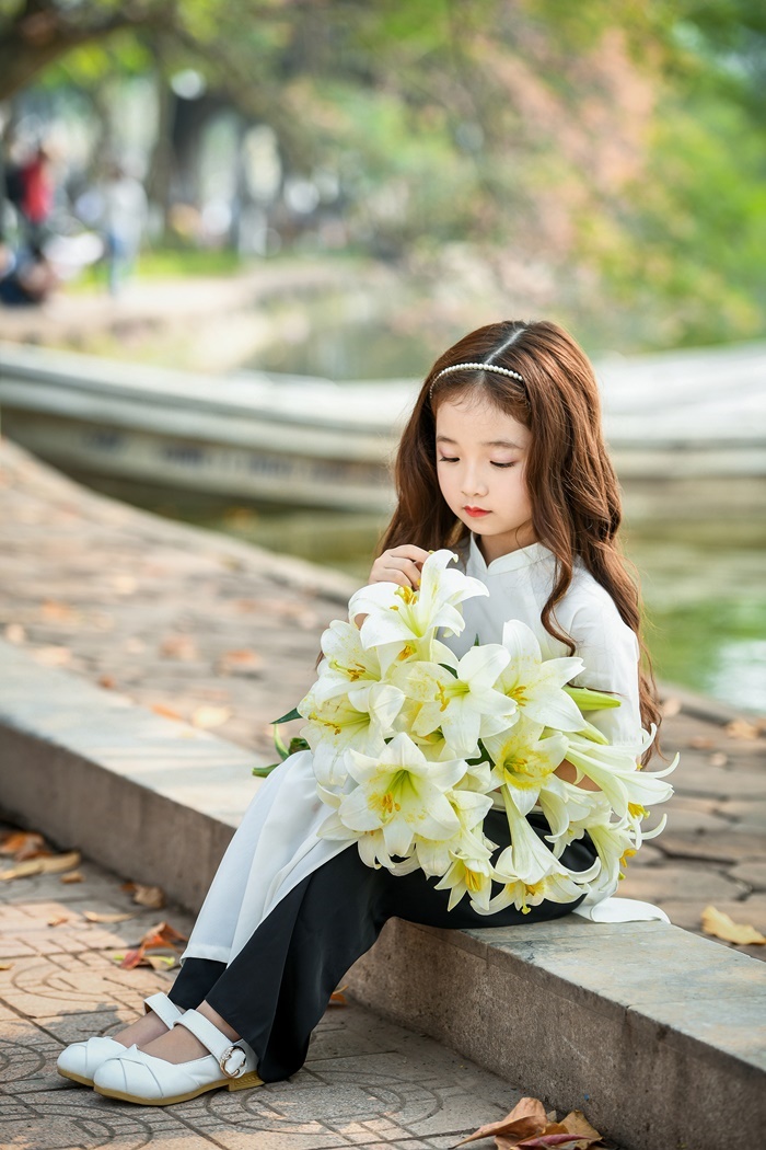 Cô bé Hà Nội trong bức ảnh này thật tuyệt vời và xinh đẹp với vẻ ngoài đằm thắm và sự ngọt ngào của hoa loa kèn. Bức ảnh này thực sự lôi cuốn sự chú ý của người xem và khiến cho ai nhìn vào cũng phải cảm thấy như mình đang chạm tay vào một chút bình yên trong cuộc sống.
