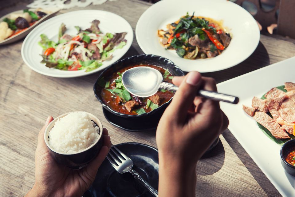 hand-holding-spoon-and-dinner-with-thailand-food-hot-and-spicy-with-herb-on-wooden-table-639948508-5a91c620642dca0036f0c212