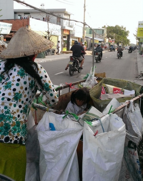 Em bé ngồi trong xe rác theo mẹ làm việc (Ảnh: Thuy Phan).