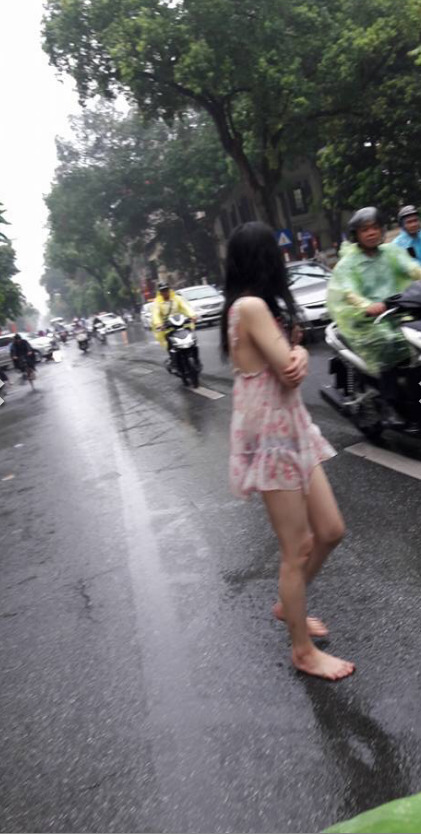 Hành động quá khó hiểu của cô gái giữa phố Hà Nội ngày mưa  - Ảnh 1.