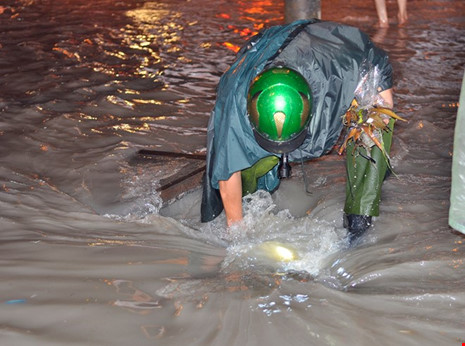 Một thượng sĩ công an đã đến cống thoát nước ven đường Đồng Khởi để móc rác, khơi thông dòng chảy.  Ảnh: zing 