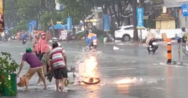 Xe máy đang đi thì bốc cháy dữ dội giữa trời mưa, cách 3 người đàn ông lúi húi dập lửa gây tranh cãi