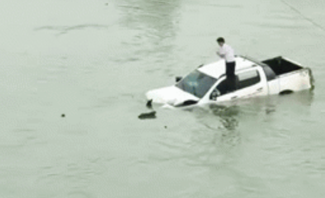 Hình ảnh tài xế trèo lên nóc xe ô tô trôi lềnh bềnh giữa sông khiến tất cả hoang mang - Ảnh 2.