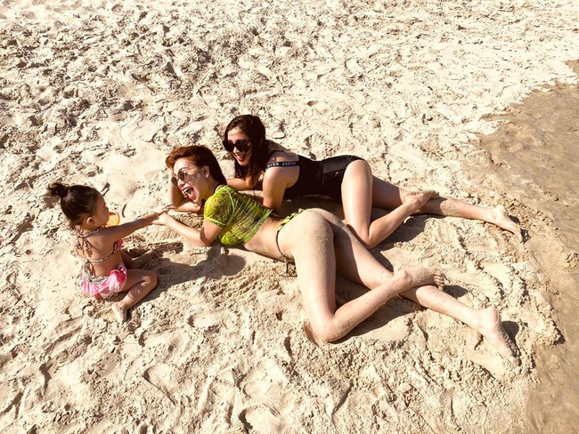 Trà Ngọc Hằng và cô bạn thân nằm trên cát nô đùa cùng con gái.