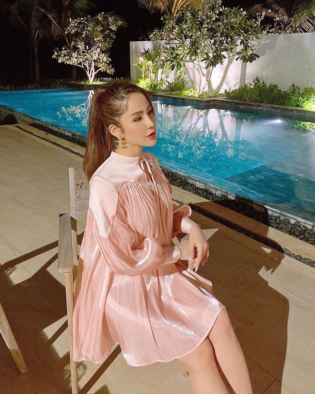 Diệp Lâm Anh mặc đầm hồng điệu đà ngồi bên cạnh bể bơi xanh trong.