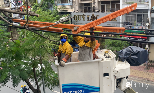 TP.HCM: Công nhân &quot;treo mình&quot; trên xe thang cao cắt cành phượng lớn bị gãy gần đường điện nguy hiểm, giữ an toàn mùa mưa bão - Ảnh 9.