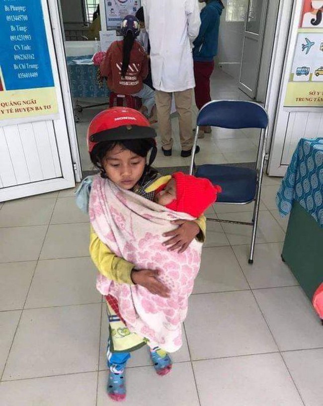 Bé gái 7 tuổi bế em đi tiêm phòng và câu chuyện phía sau khiến nhiều người xúc động - Ảnh 1. Bé gái 7 tuổi bế em đi tiêm phòng và câu chuyện phía sau khiến nhiều người xúc động - Ảnh 1.