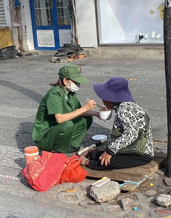 Hình ảnh cô thanh niên xung phong đút thức ăn cho bà cụ khuyết tật khiến người xem ấm lòng. - Ảnh 1.