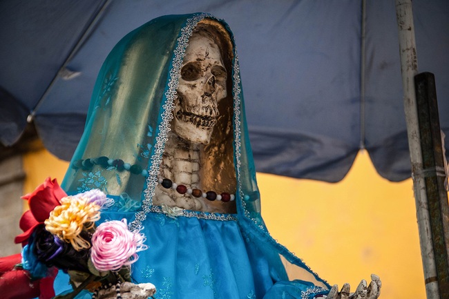 The image of an unbelievably scary-looking skeleton decorated with flowers is a symbol of hope and a little-known story about the goddess of 