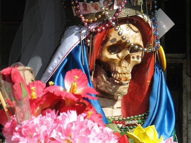 The image of an unbelievably scary-looking skeleton decorated with flowers is a symbol of hope and a little-known story about the goddess of 