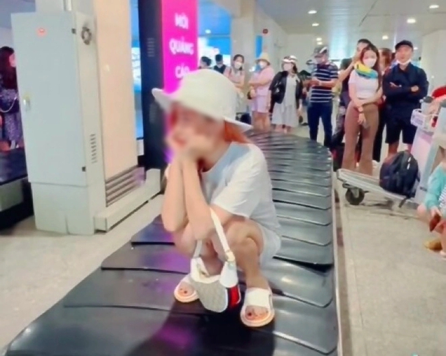 Có thể cấm bay cô gái ngồi trên băng chuyền hành lý sân bay quay clip - Ảnh 1.