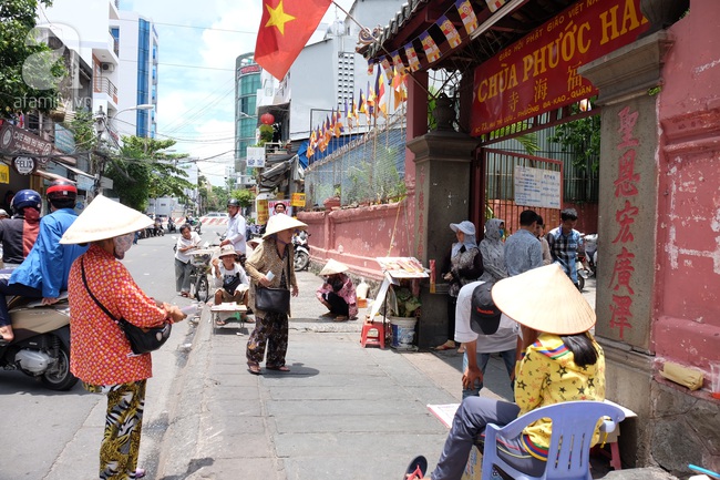 Người người đi lễ trong mùa Phật Đản, riêng em theo mẹ bán hàng rong trước cổng chùa - Ảnh 1.