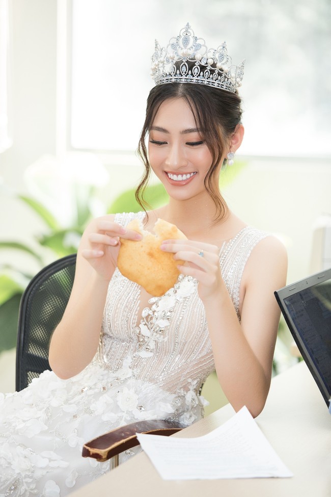 Hoa hậu Lương Thùy Linh đầu đội vương miện, tay bóc bánh ăn vội mà vẫn đáng yêu lạ thường  - Ảnh 2.
