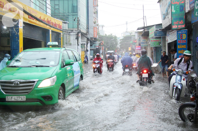 Mưa lớn kéo dài hơn 30 phút, người Sài Gòn bì bõm lội nước, té ngã vì nhiều tuyến đường ngập nặng - Ảnh 10.
