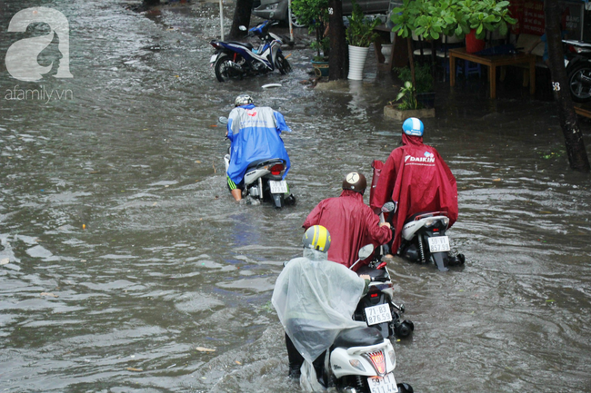 Mưa lớn kéo dài hơn 30 phút, người Sài Gòn bì bõm lội nước, té ngã vì nhiều tuyến đường ngập nặng - Ảnh 12.