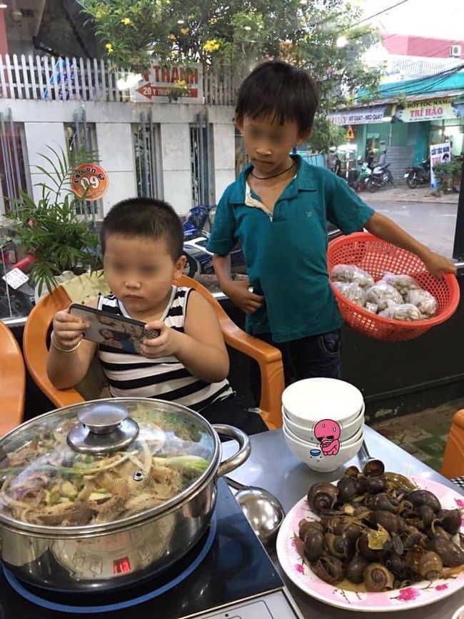 1 bức ảnh, 2 số phận: Hình ảnh cậu bé bán hàng rong lặng lẽ xem ké điện thoại của người bạn cùng tuổi bên bàn lẩu khiến nhiều người xót xa - Ảnh 1. 1 bức ảnh, 2 số phận: Hình ảnh cậu bé bán hàng rong lặng lẽ xem ké điện thoại của người bạn cùng tuổi bên bàn lẩu khiến nhiều người xót xa - Ảnh 1.