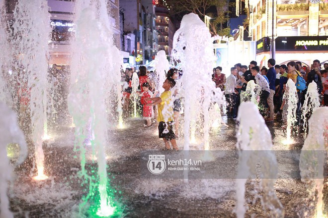 Sài Gòn tối mùng 1 Tết: Trẻ em thích thú cởi áo, nhảy vào đài phun nước đường hoa Nguyễn Huệ để nô đùa - Ảnh 12.