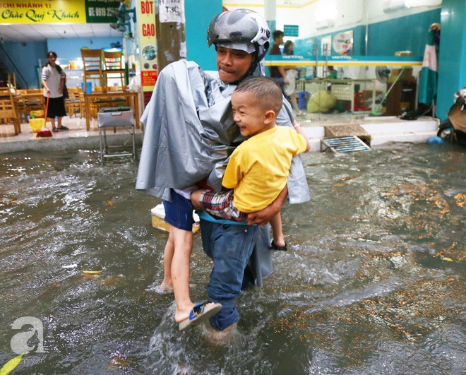 Sài Gòn sau cơn mưa khủng, bố mẹ bì bõm lội nước bế con đi học về - Ảnh 3.