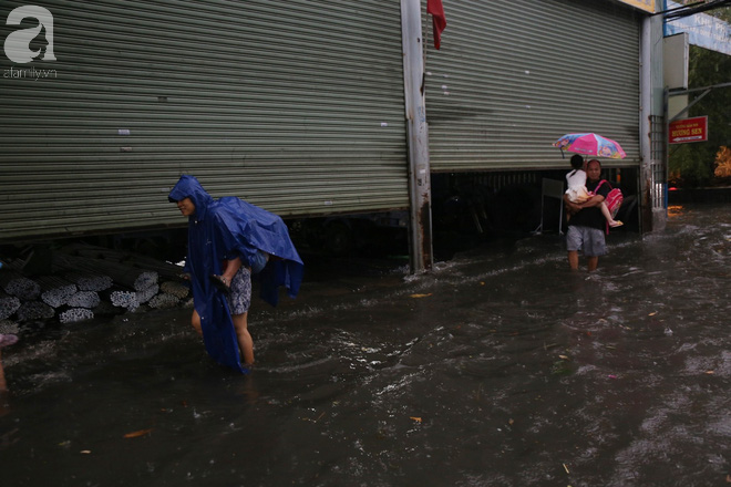 Sài Gòn sau cơn mưa khủng, bố mẹ bì bõm lội nước bế con đi học về - Ảnh 6.