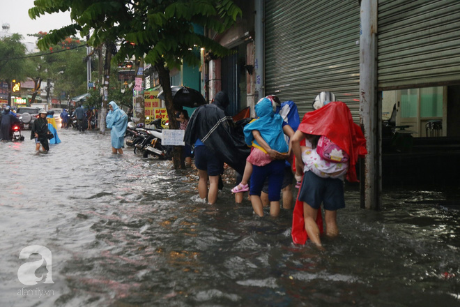 Sài Gòn sau cơn mưa khủng, bố mẹ bì bõm lội nước bế con đi học về - Ảnh 7.