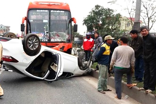 Xe khách tông xe con lật ngửa trên quốc lộ, 3 nạn nhân mắc kẹt bên trong - Ảnh 1.