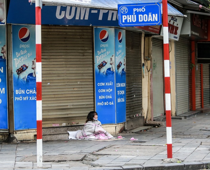 Những ngày Hà Nội vắng vẻ bởi cách ly xã hội, đâu đó nơi góc phố cổ là hình ảnh bé gái lủi thủi trên tấm bìa giấy giữa trời mưa phùn giá rét - Ảnh 1.