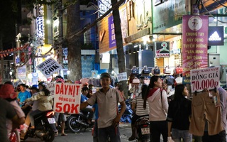 Nhiều nhân viên cửa hàng thời trang ở Sài Gòn cầm bảng giá tràn ra đường chào mời khách dịp cận Tết