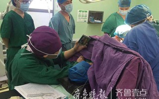 Y tá ân cần quỳ bên bàn mổ suốt cả tiếng đồng hồ để cầm điện thoại cho bệnh nhi xem hoạt hình