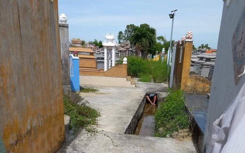 Người đàn ông bị bỏng nặng nằm dưới mương nước trong nghĩa trang