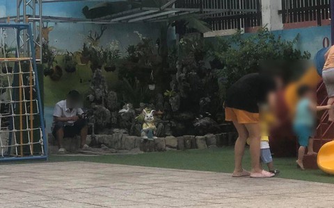 Bức ảnh ông bố ở TP.HCM ngồi trong sân trường nhìn qua rất bình thường, nhưng thứ cầm trên tay gây tranh cãi