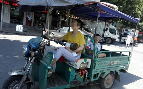 Vừa lái xe vừa cho con bú, lại chở thêm bé nữa đằng sau, mẹ trẻ gây tranh cãi dữ dội