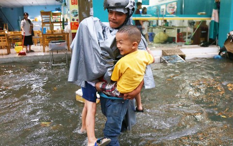 Sài Gòn sau cơn mưa "khủng", bố mẹ bì bõm lội nước bế con đi học về